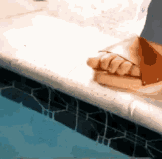 a person 's foot is sitting on the edge of a pool