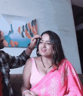 a woman in a pink saree is being touched by a man on a couch