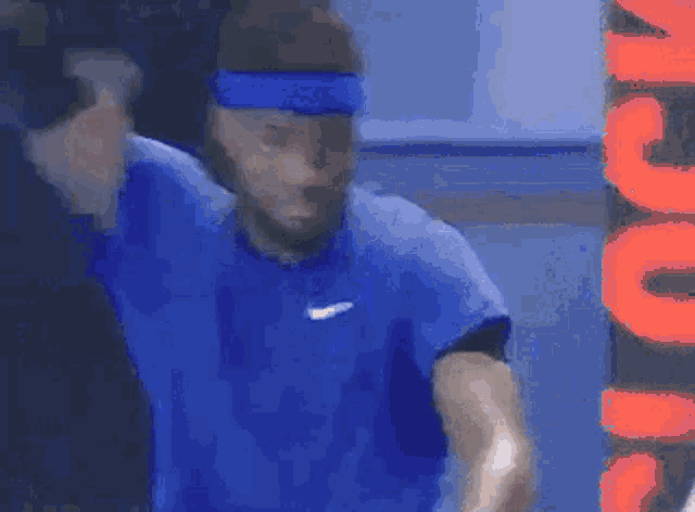 a tennis player wearing a blue headband is playing tennis .