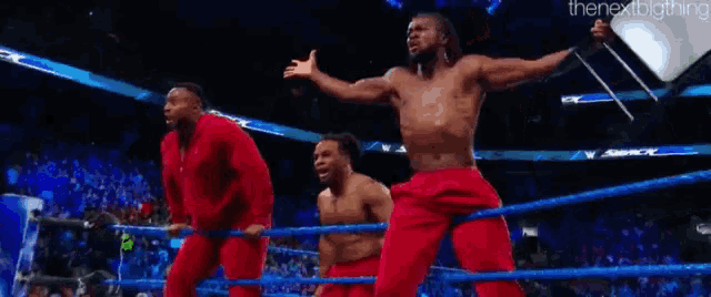 three men are dancing in a wrestling ring .