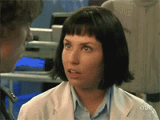 a woman in a white lab coat is talking to another woman