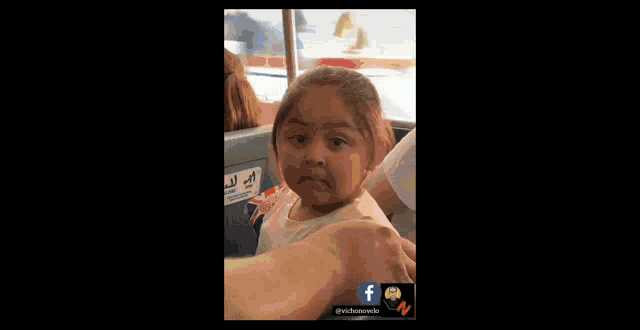 a little girl is making a funny face while sitting on a bus .
