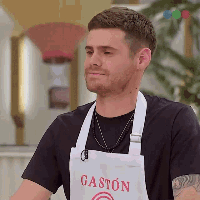a man wearing a white apron with gaston written on it