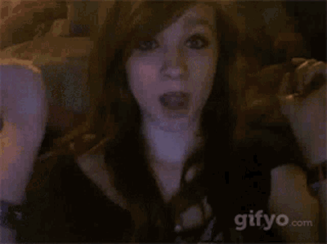 a woman is making a funny face in front of a gifyo.com advertisement