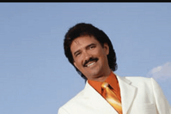 a man in a white suit and orange tie smiles for the camera