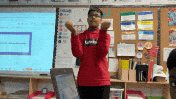 a boy in a red levi 's sweatshirt stands in front of a white board