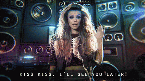 a woman says kiss kiss i 'll see you later in front of a wall of speakers