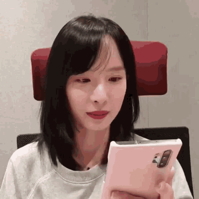 a woman sitting in a chair holding a cell phone