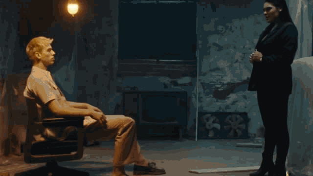 a man is sitting in a chair while a woman stands behind him