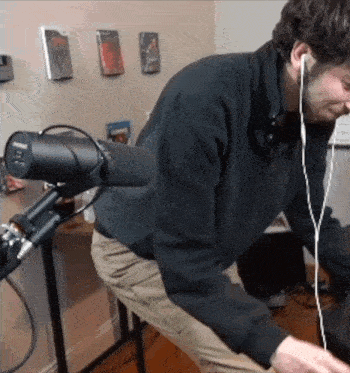 a man wearing headphones and a shure microphone looks at something
