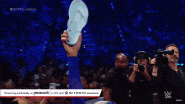 a woman in a blue outfit is holding a box of money in front of a crowd of people .
