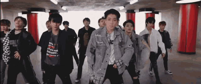 a group of young men are dancing in a hallway with red pillars
