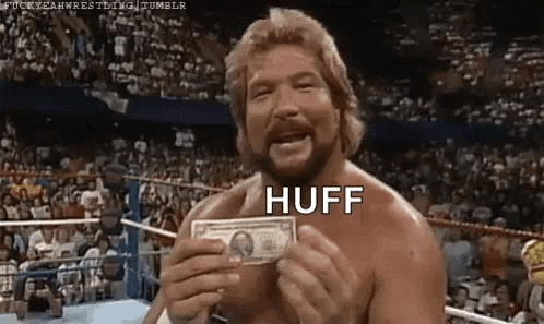 a shirtless wrestler is holding a dollar bill in a boxing ring .