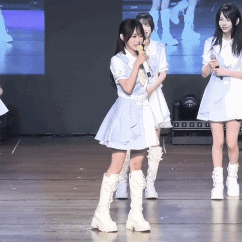 a girl singing into a microphone while standing on a stage