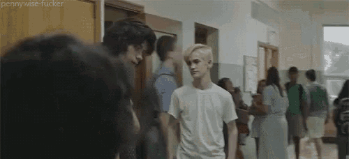 a group of people are standing in a hallway .