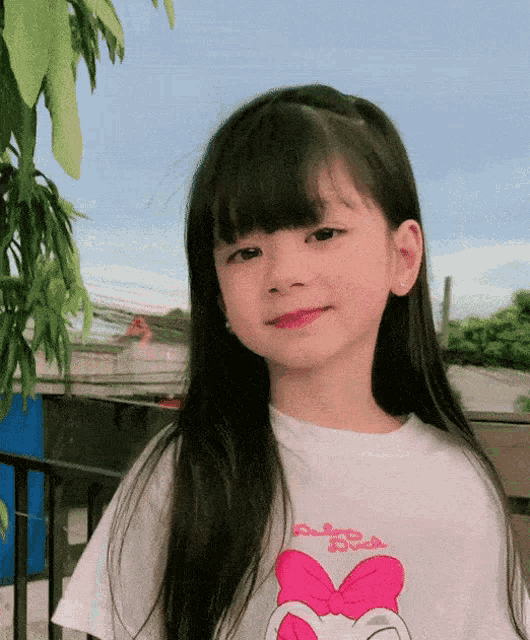 a little girl wearing a t-shirt with a pink bow on it