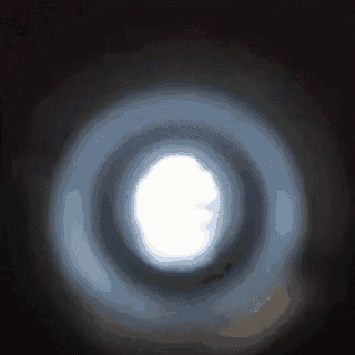 a light is shining through a hole in a dark room