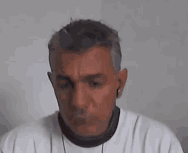 a man wearing ear buds and a white shirt is looking at the camera