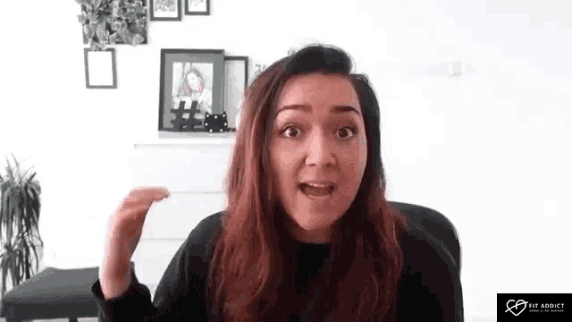 a woman is sitting in a chair and making a funny face while talking on a video call .