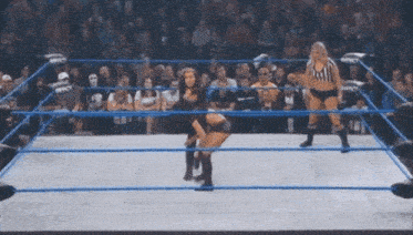 two women are wrestling in a wrestling ring with a referee watching