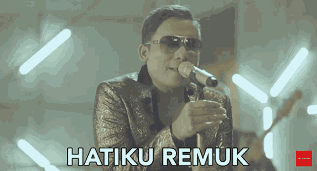 a man singing into a microphone with the words hatiku remuk written below him