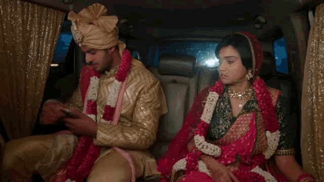 a bride and groom sitting in the back of a car