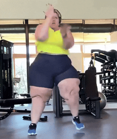 a woman is dancing in a gym wearing shorts and a yellow tank top