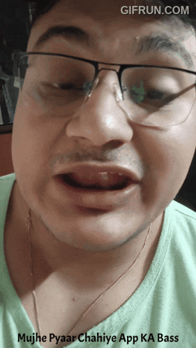a man wearing glasses and a green shirt is making a funny face