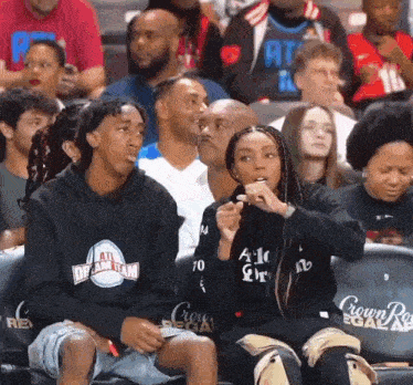 a man and a woman are sitting in the stands at a basketball game .