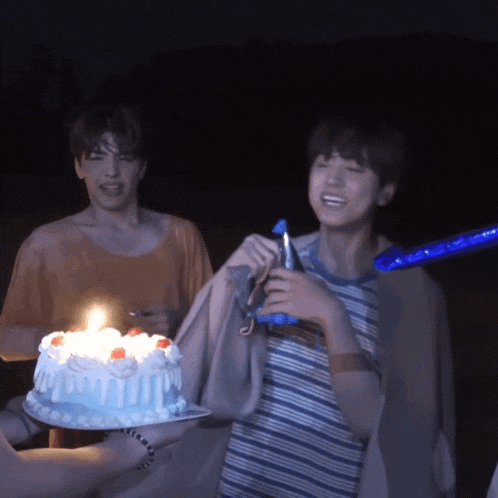 a man is holding a birthday cake with a lit candle on it