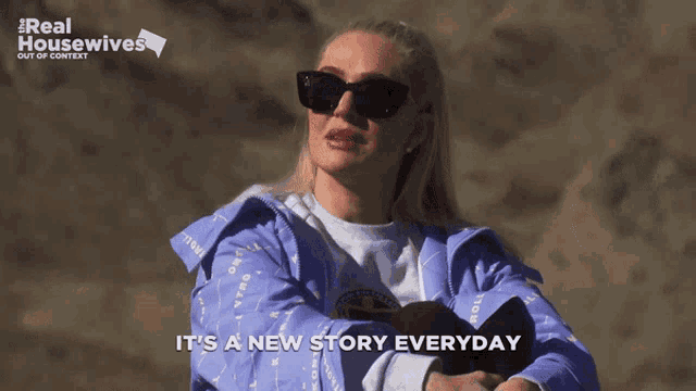 a woman wearing sunglasses and a blue jacket with the words it 's a new story everyday