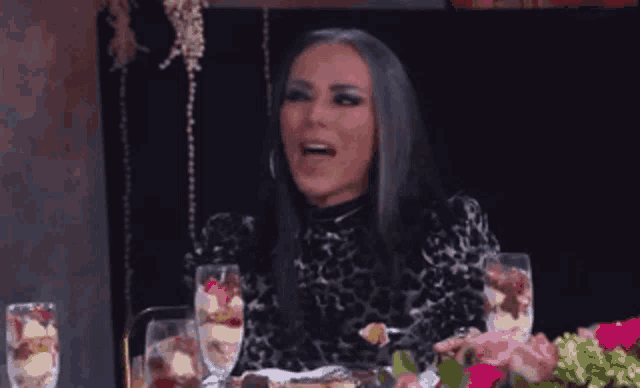 a woman is sitting at a table with a plate of food and a glass of wine .