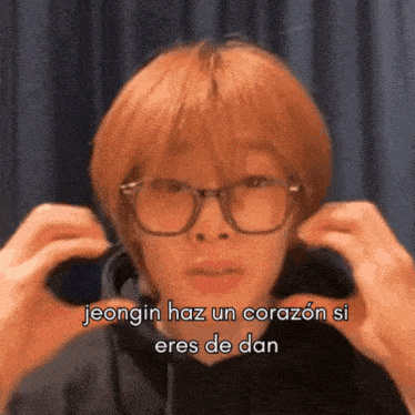 a man wearing glasses is making a heart shape with his hands and says jeongin haz un corazón si eres de dan
