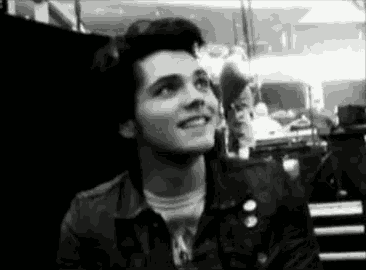 a black and white photo of a young man smiling in a dark room .