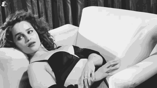 a black and white photo of a woman laying on a couch with the letter e behind her
