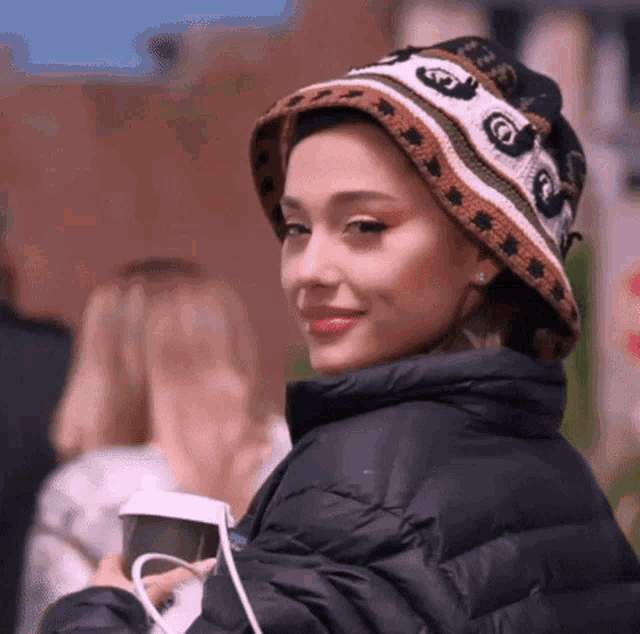 ariana grande is wearing a bucket hat and a black jacket .