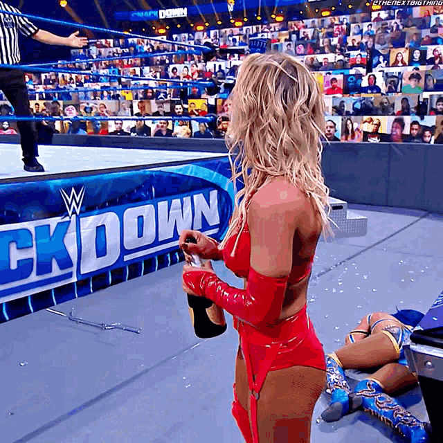 a woman in a red outfit is holding a bottle of champagne in front of a sign that says " ckdown "
