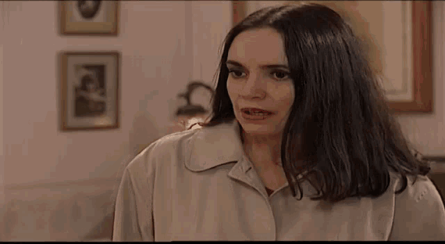 a woman in a trench coat is standing in a living room .
