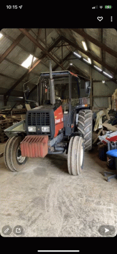 a black and red tractor is parked in a warehouse