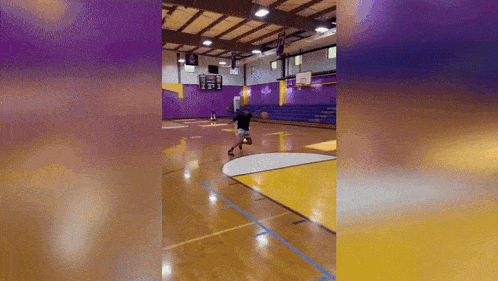 a person is playing basketball in a gym with a purple wall
