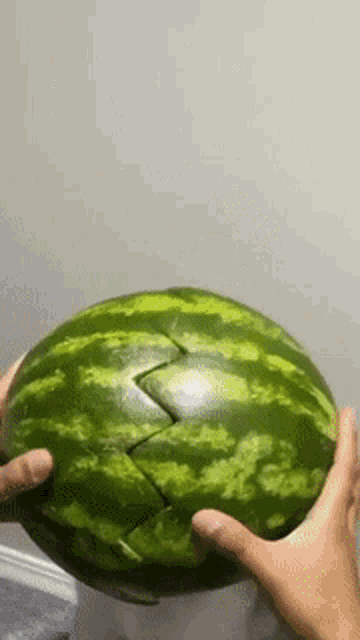 a person is holding a watermelon in their hands that has been cut in half