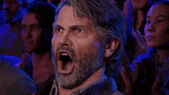 a man with a beard is making a funny face in front of a crowd