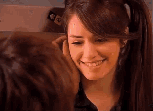 a woman with pigtails is smiling while a man holds her face