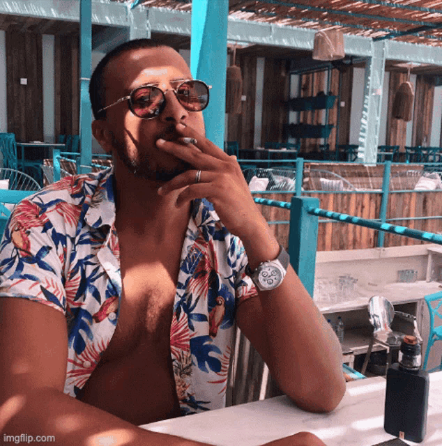 a shirtless man smoking a cigarette while wearing sunglasses and a watch