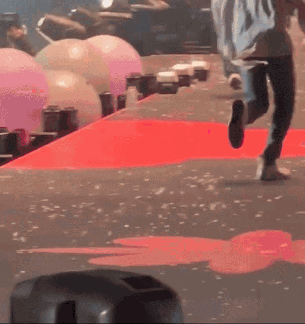 a person running on a red carpet with balloons on it