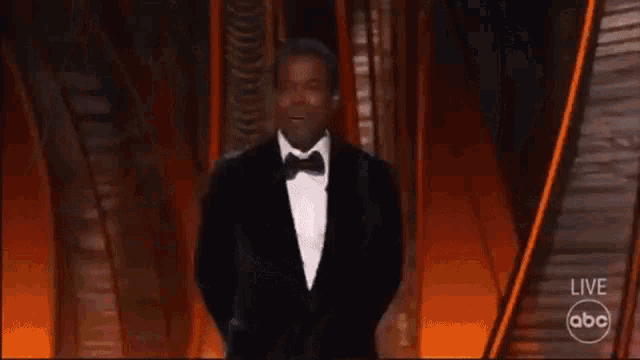a man in a tuxedo is standing on a stage in front of an audience with abc written on the bottom of the screen