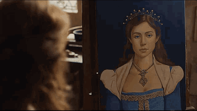 a woman is looking at a painting of a woman with a tiara on her head