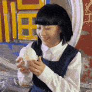 a girl in a school uniform is smiling while holding a sandwich