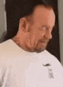 a man with a beard is wearing a white t-shirt with a mustache on the front .