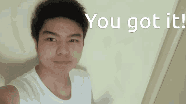 a young man in a white tank top is standing in front of a wall that says you got it
